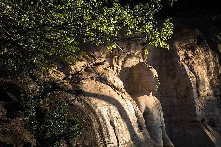 Primo piano dell'espressione serena del volto e del gesto della mano Asisa Mudra del Buddha di Aukana