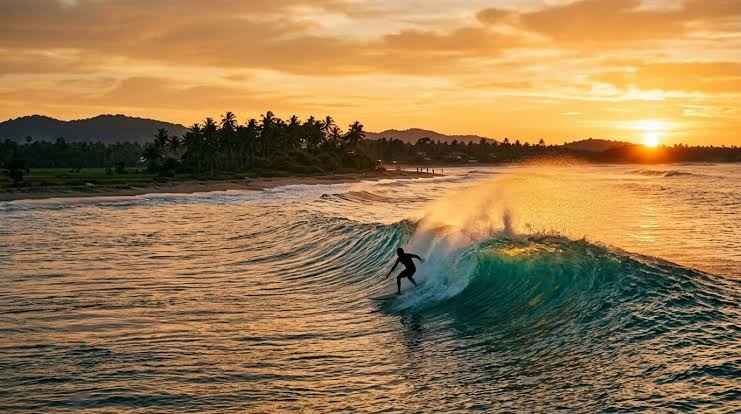Surfista che cavalca un'onda al tramonto ad Arugam Bay, una delle principali destinazioni per il surf in Sri Lanka
