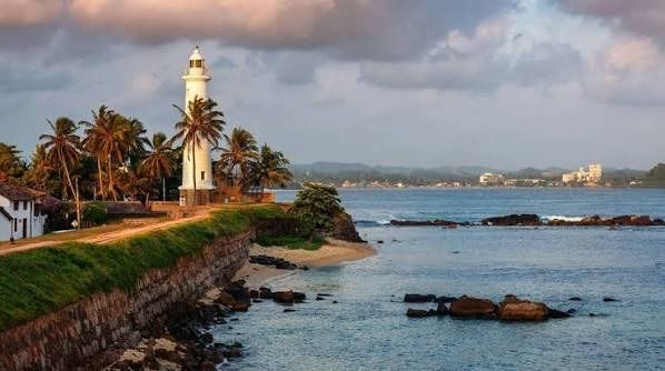 Galle Fort lighthouse against a golden ocean sunset in southern Sri Lanka.