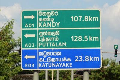 Trilingual road and railway signage showing Sinhala, Tamil, and English in Sri Lanka.