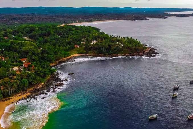 Aerial panoramic view of the lush coastal peninsula and deep blue ocean around Gandara Beach, Sri Lanka
