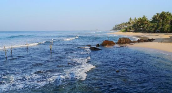 Traditional wooden stilt fishing poles standing in the shallow reef waters along the tranquil shore of Gandara Beach