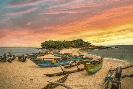 Traditional fishing boats resting on Nilwella beach under a spectacular fiery sunset sky
